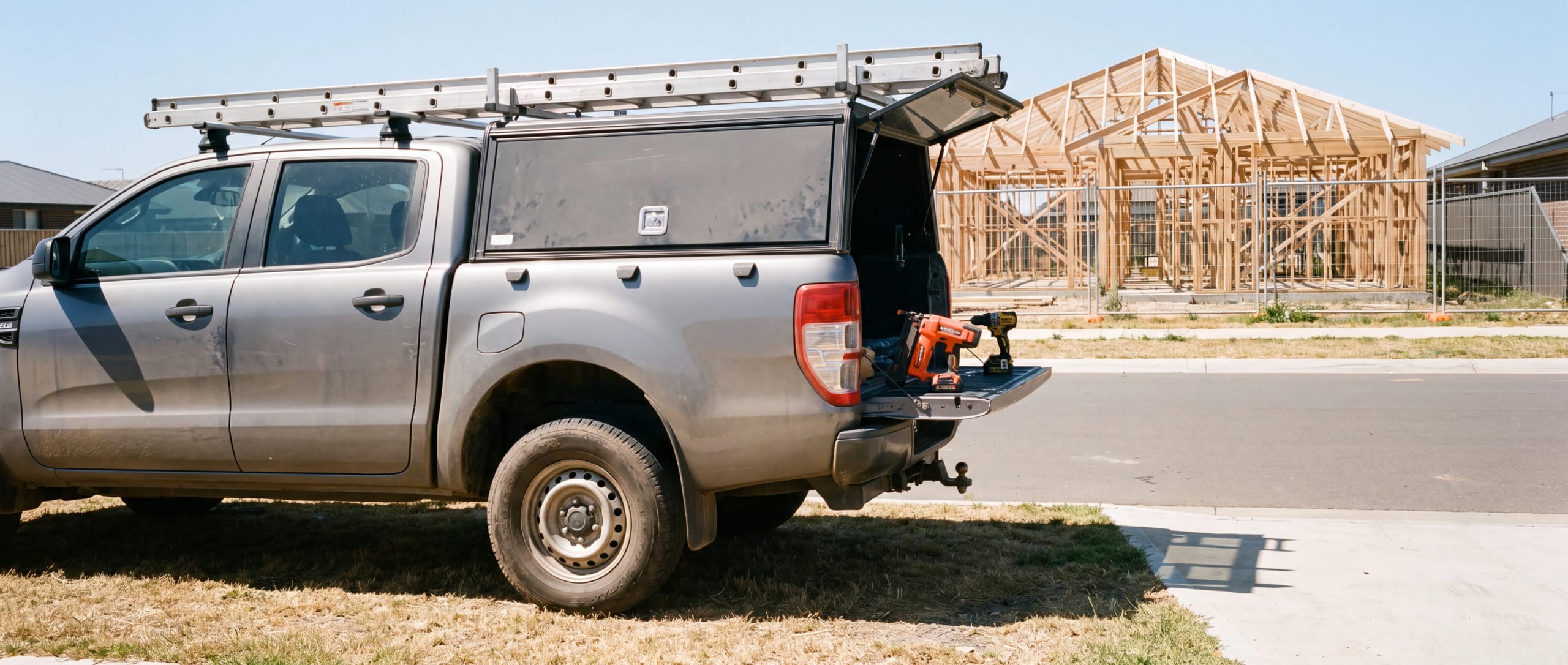 Work ute with ladder racks and tools beside a house under construction