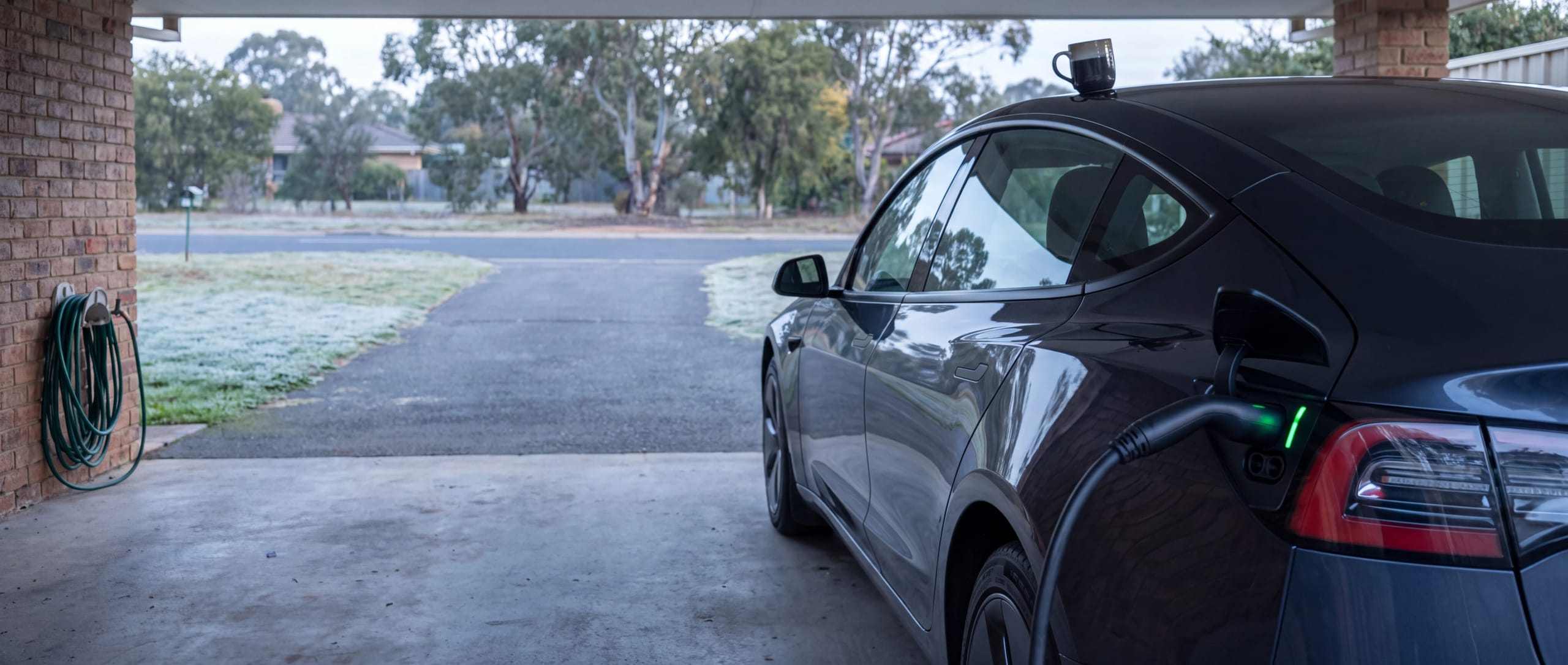 Electric car charging in a home carport on a frosty morning