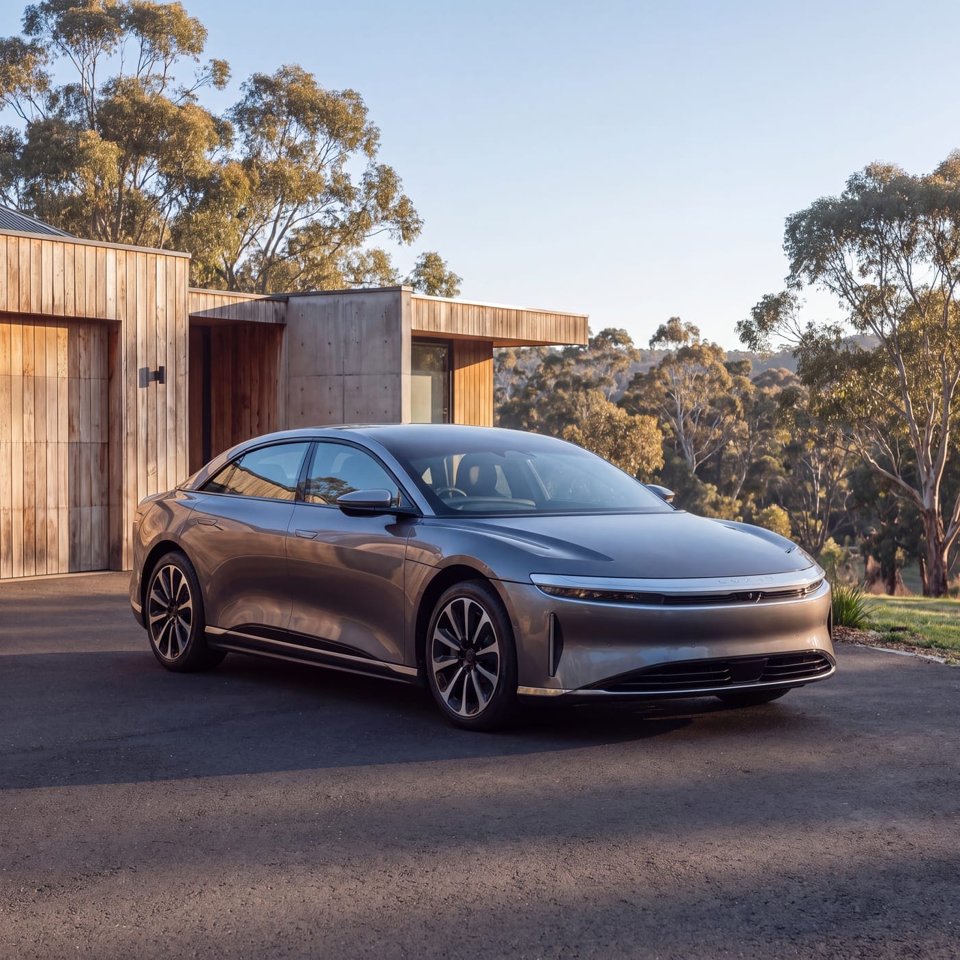 Silver electric sedan parked in front of a modern timber and concrete house