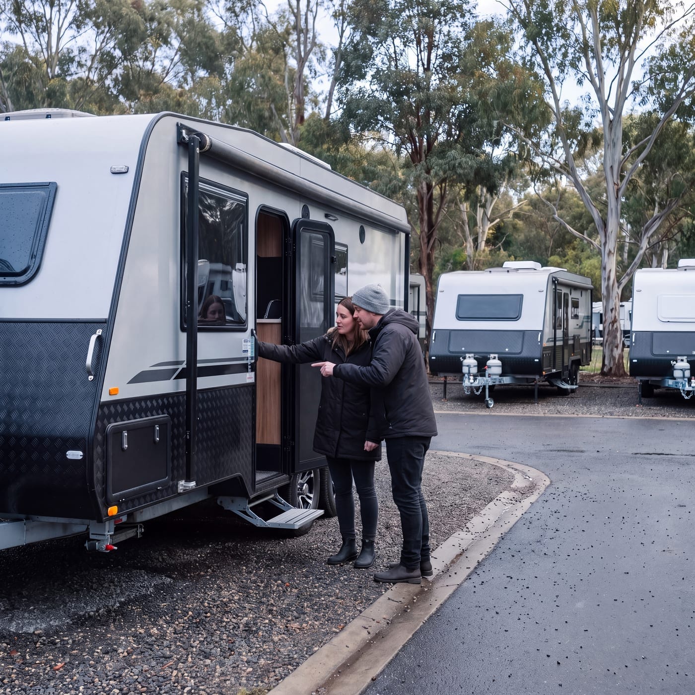 Two people stepping up into the doorway of a caravan parked in a row of vans