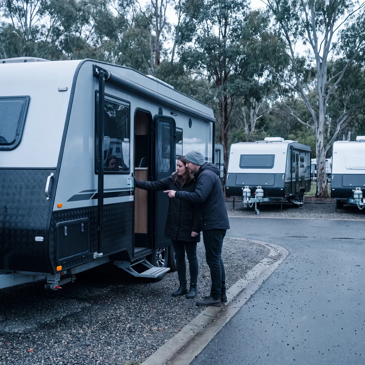 Couple looking into the doorway of a new caravan in a sales yard