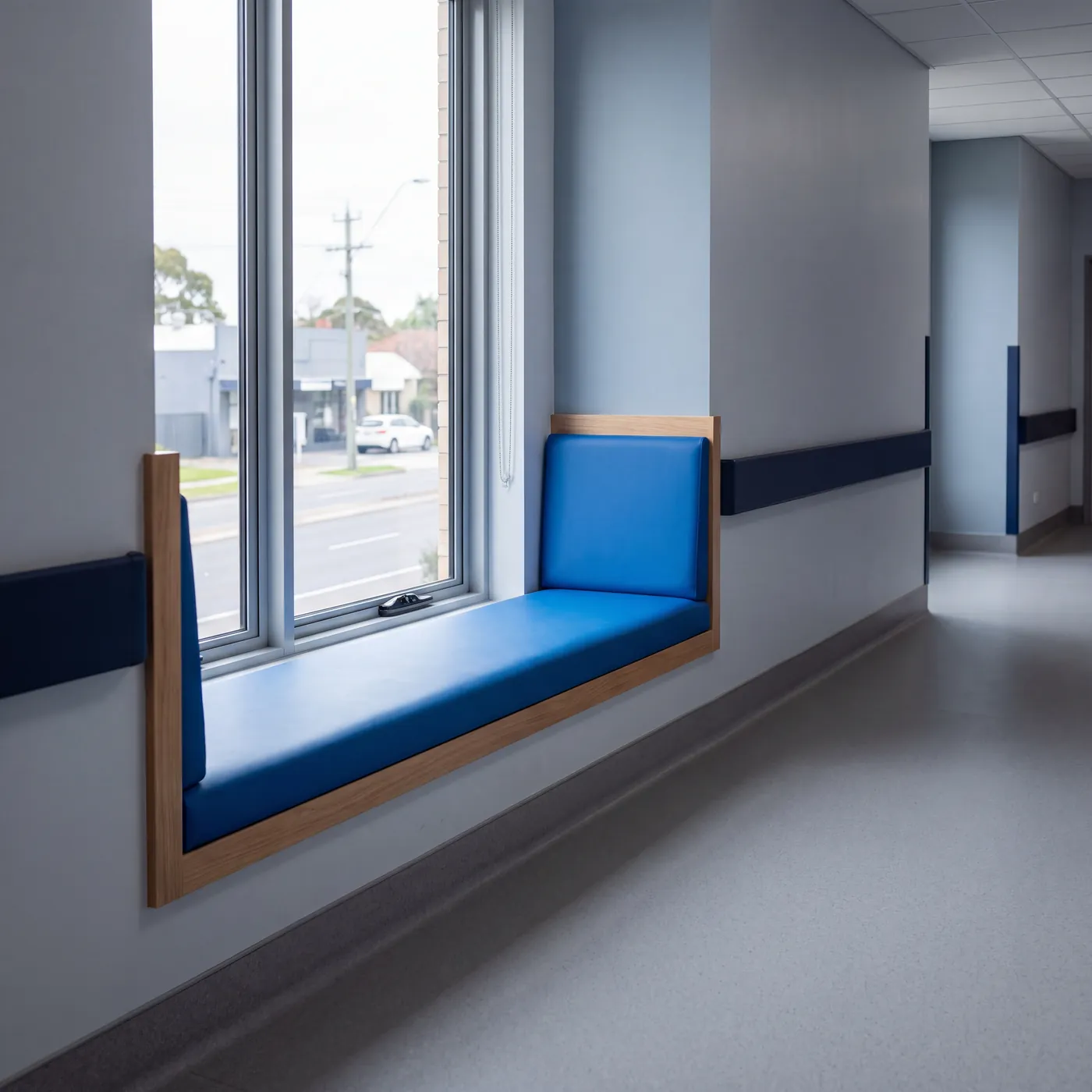 Hospital corridor with a window seat and a handrail along the wall
